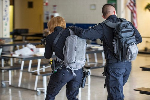 5.11 UCR SlingPack Active Shooter Response Kit, carried by RTF first responder with a gun walking through halls during an active shooter staged scenario